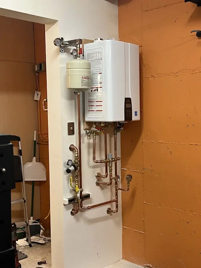Plumbing technician inspecting water heater connections in Oneonta